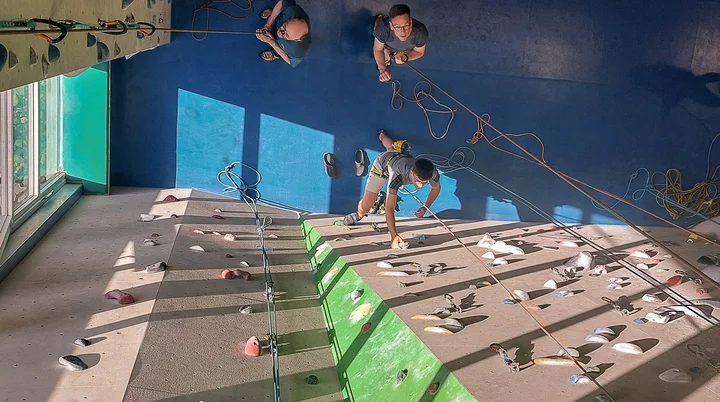 Die Kamera filmt von oben nach unten Kletterer und Sichernde in einer Kletterhalle | © Sektion/Konrad Eutebach