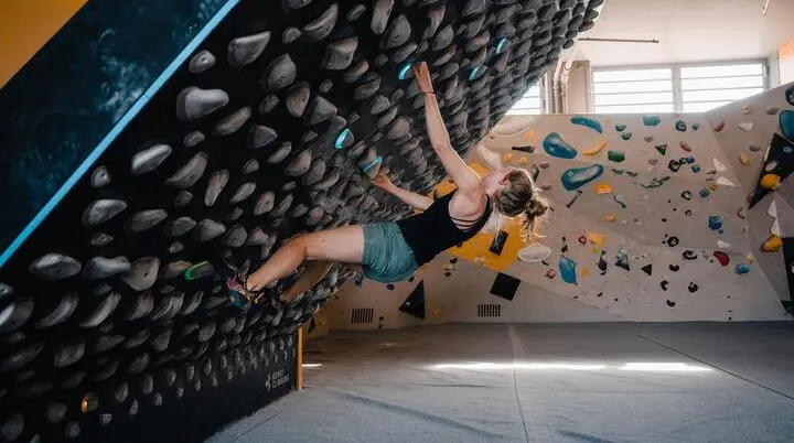 Bouldern am Kilterboard: Eine Frau bewegt sich an einer schräg gestellten Kletterwand, einem sogenannten Kilterboard | © DAV/Marisa Koch