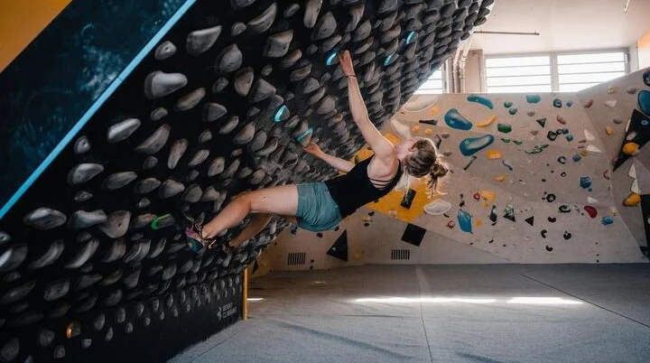 Bouldern am Kilterboard: Eine Frau bewegt sich an einer schräg gestellten Kletterwand, einem sogenannten Kilterboard | © DAV/Marisa Koch