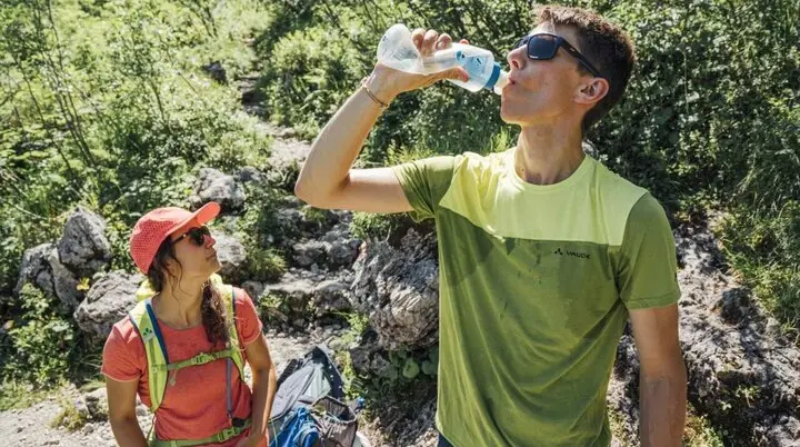 Zwei Wanderer rasten bei heißen Temperaturen und trinken aus einer Flasche | © DAV / Julian Rohn